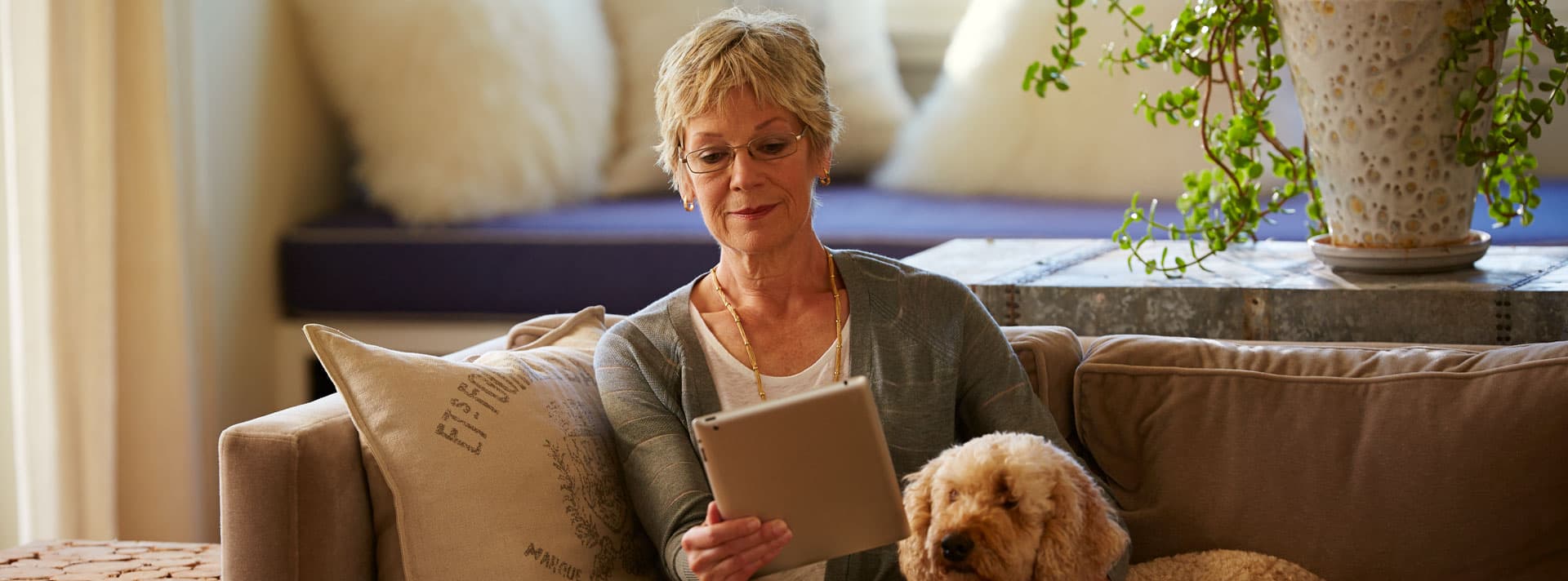 Woman reading with dog on couch